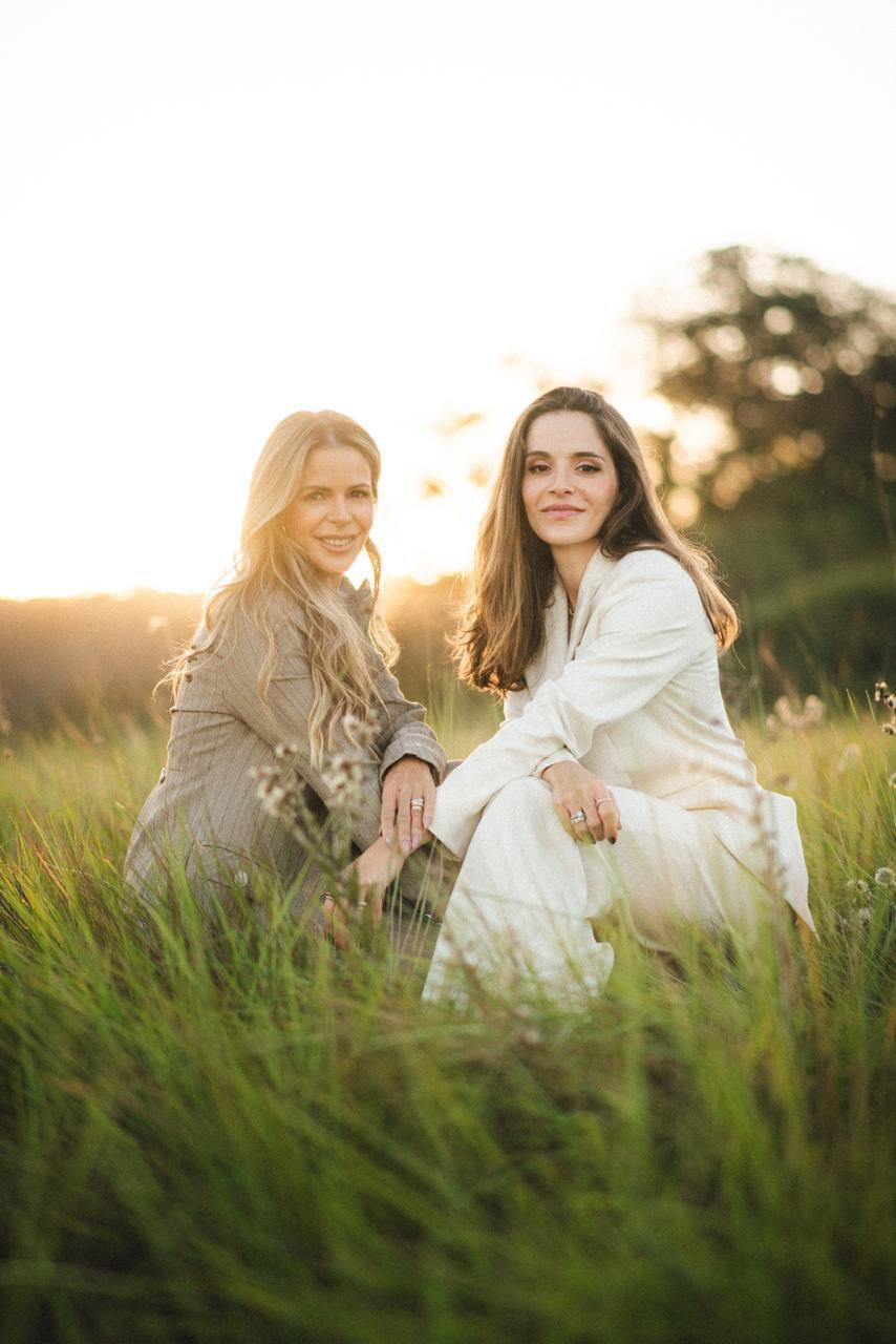 Duas mulheres caminhando em um campo ao pôr do sol